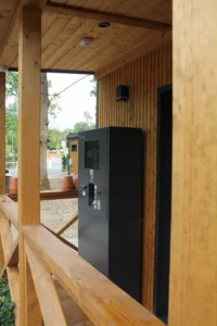 Grauer Check-In Automat vor einem Gebäude mit Holzfassade