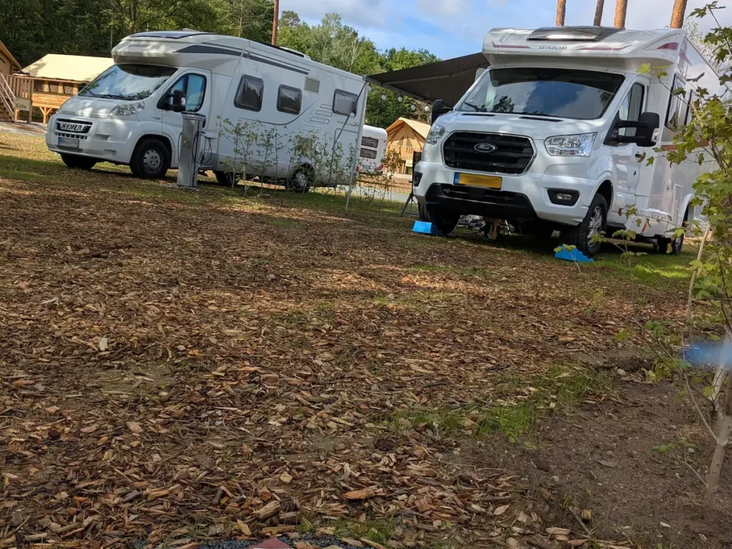 Zwei Wohnmobile auf ihrem Stellplatz - im Hintergrund sind Safari Lodges sehen
