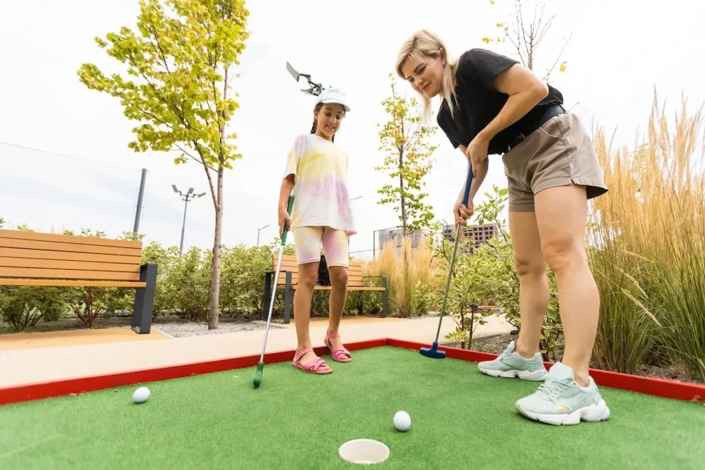 Eine Frau und ein Mädchen spielen gemeinsam Minigolf