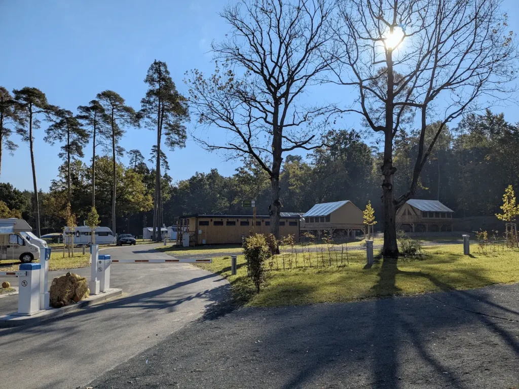 Campingplatz vor einer Schranke mit Wohnwagen, Sanitärhaus und Safari Lodges