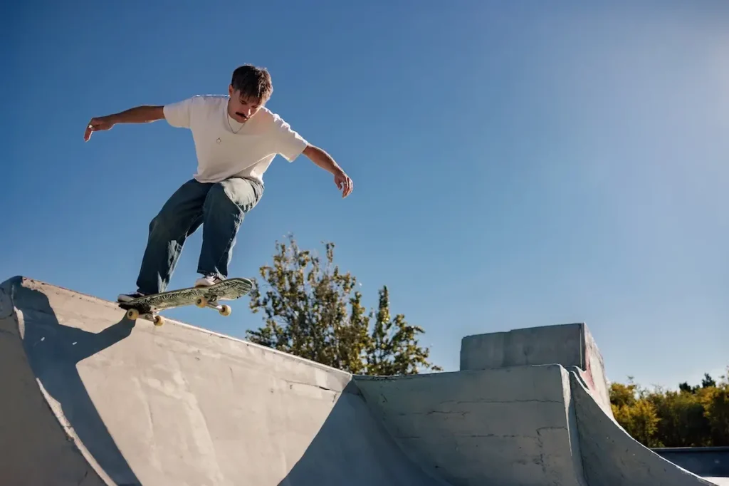 Ein Mann steht auf seinem Skateboard an der Rail von einer Quaterpipe
